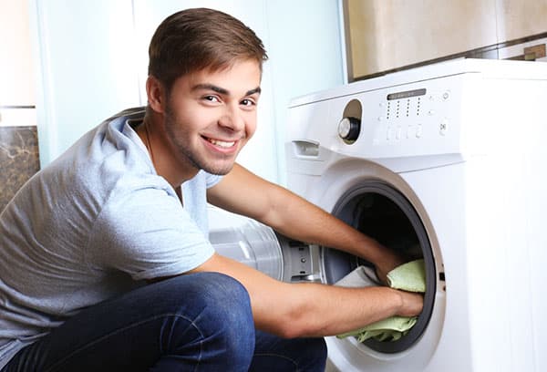 Ein Mann holt Wäsche aus einer Waschmaschine
